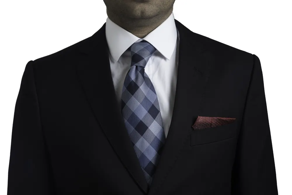 Detail of a bespoke black suit with white shirt and check tie