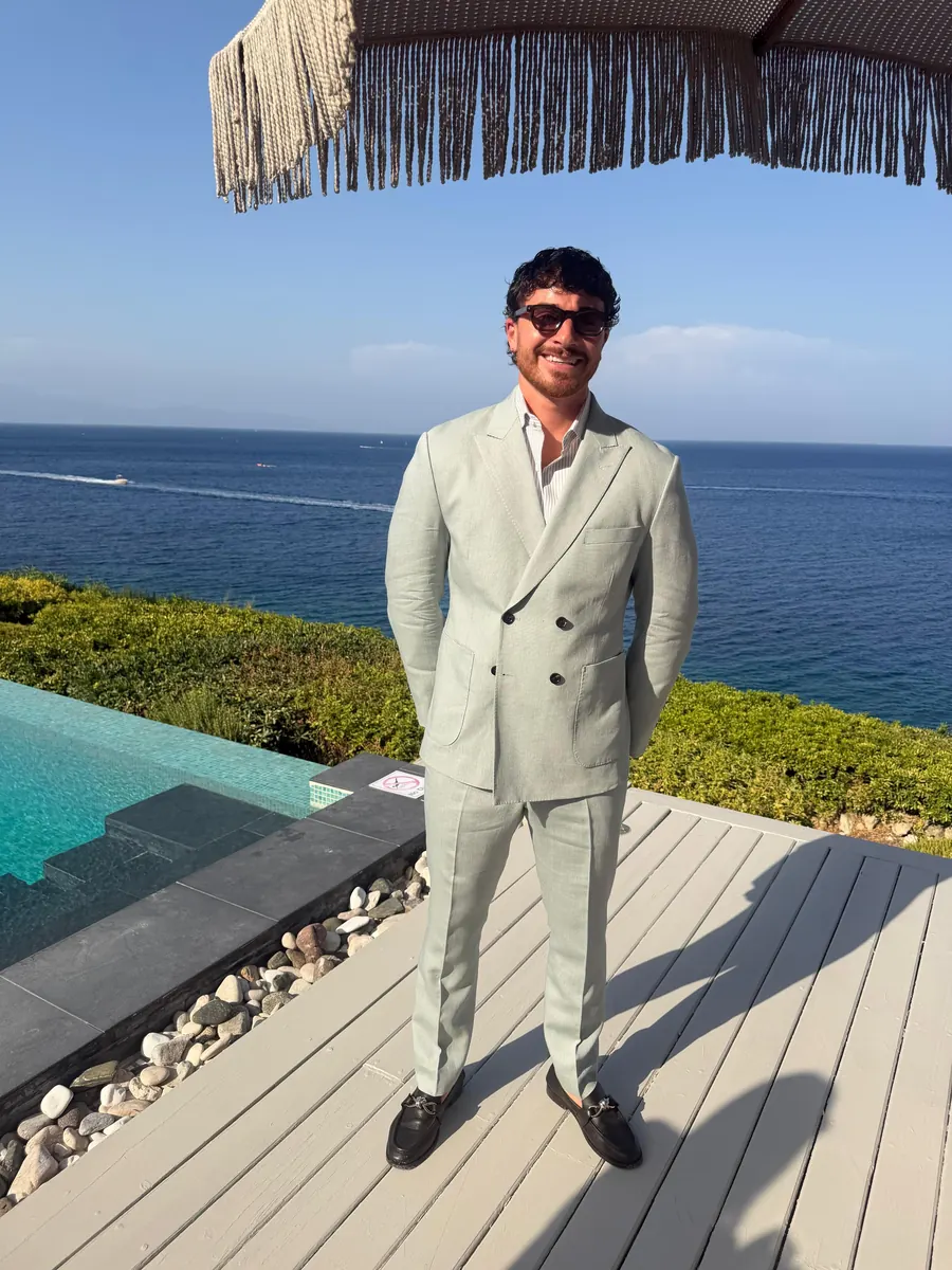 Client in a bespoke sage linen double-breasted suit by the sea